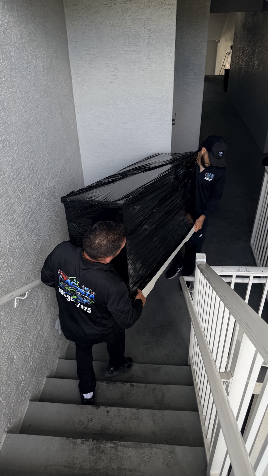 Acosta Services Group team carefully carrying wrapped furniture down apartment stairs