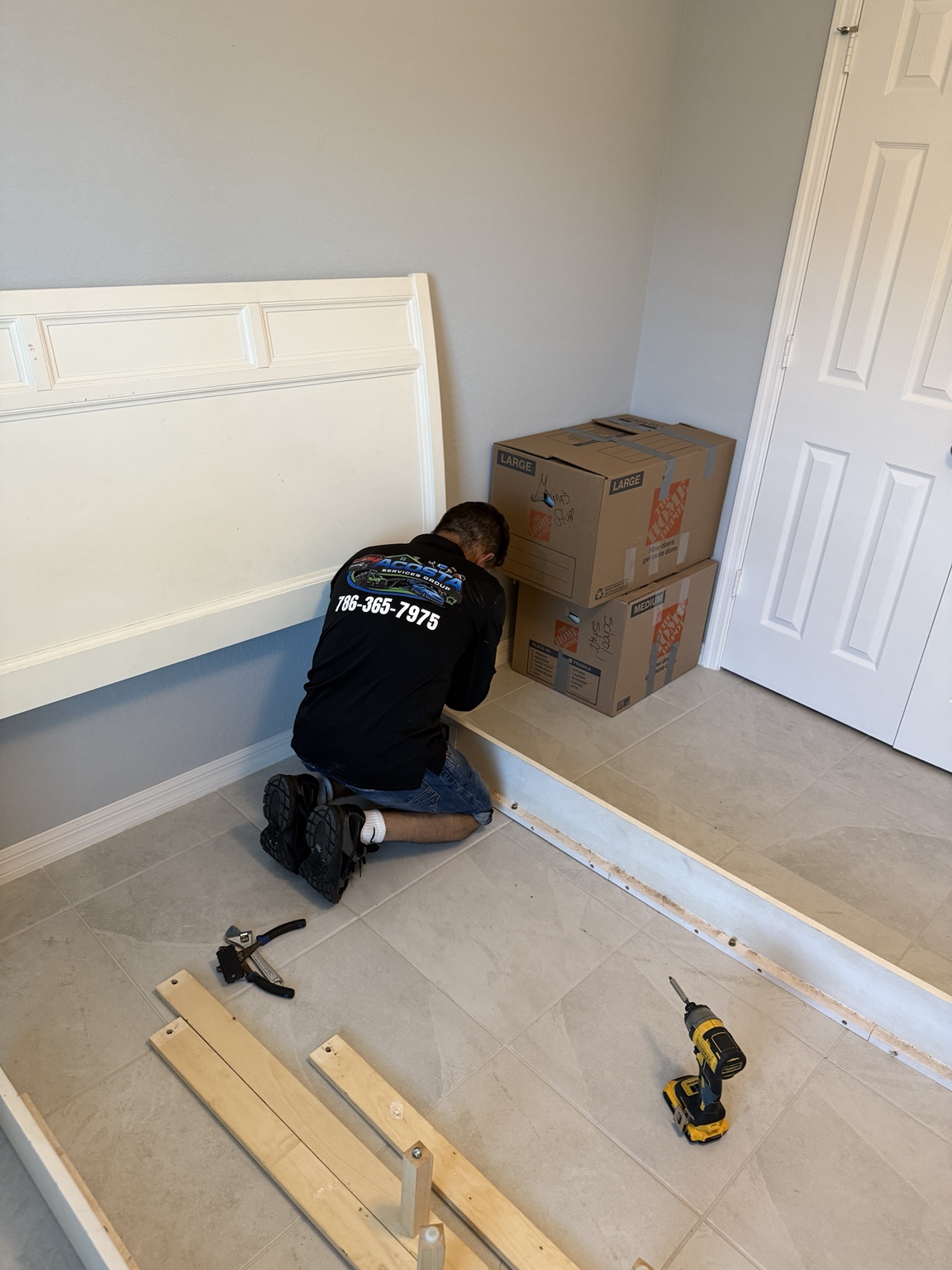 Acosta Services Group assembling a large wooden bed frame inside a customer bedroom