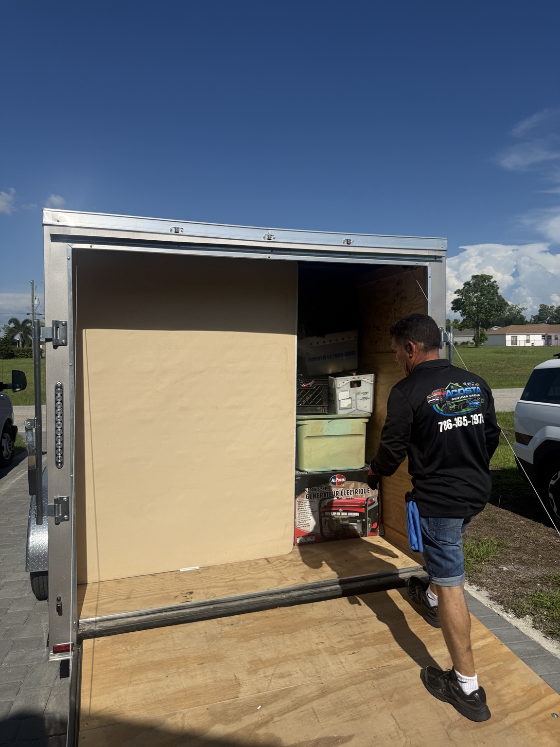 Acosta Services Group team member unloading household items from an enclosed moving trailer